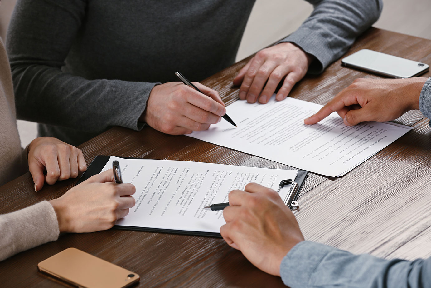 two hands with pens pointing at Legal documents